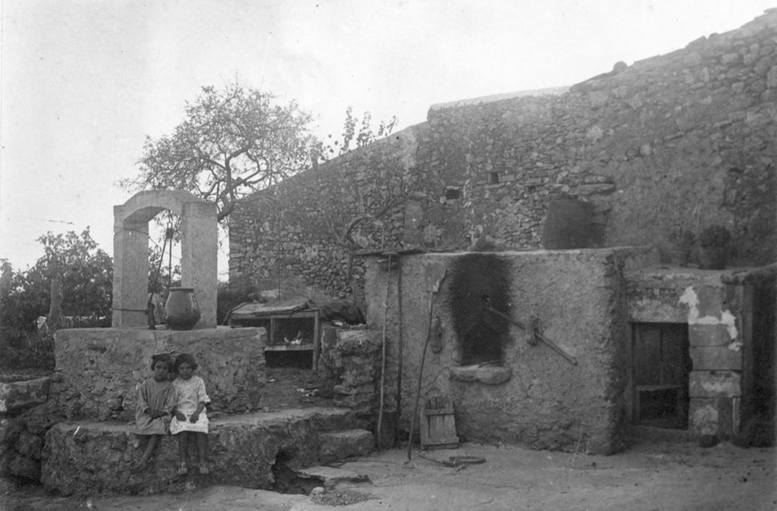 Dues nenes davant d'un pou i un forn a Calonge