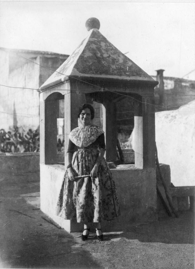 Chica con traje de mudar tradicional frente a un pozo