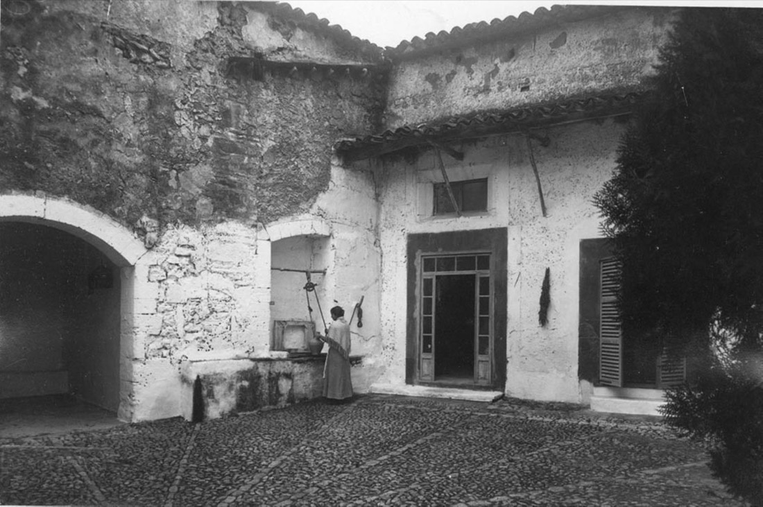 Pati d'una casa de Pollença amb una dona traient aigua d'un pou