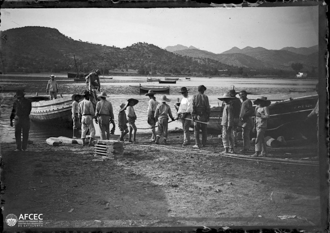 Pescadores y embarcaciones en una playa y parte de la costa